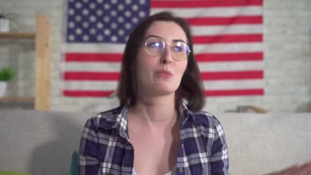 アメリカ国旗の背景にシャツを着た若い女性ブロガーがビデオをクローズアップ — ストック動画