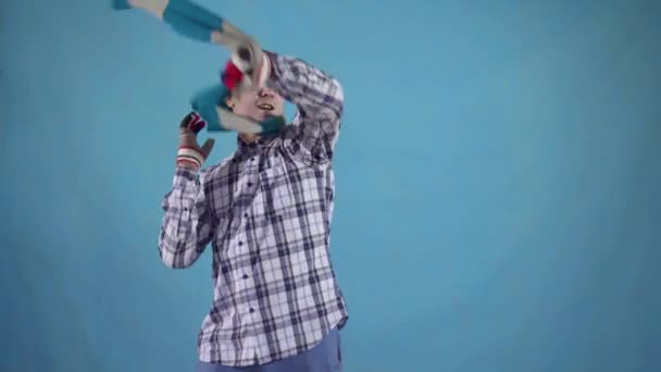 Frozen man covered with frost takes off his scarf and gloves from the heat standing on a blue background — Stock Video