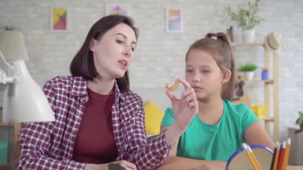 Молодая женщина рассказывает девочке-подростку о слуховом аппарате — стоковое видео