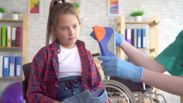 Médico ortopédico diz a uma adolescente sobre palmilhas ortopédicas de perto — Vídeo de Stock