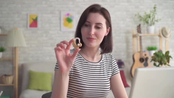 Young woman looking for information on the Internet in a laptop and holding a hearing aid close up — Stock Video