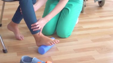 Doktor ortopedik sorunlar ile bir tekerlekli sandalyede bir genç kız yardımcı olur düz ayak düzeltmek için egzersizleri yapmak için yavaş Mo yakın
