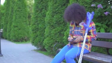 bir tezgah yakın yukarı oturan koltuk değneği ile kırık bir bacak ile bir afro saç modeli ile Afrikalı Amerikan kadın