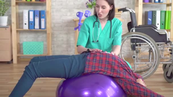 Fisioterapeuta no centro de reabilitação ajuda uma adolescente em reabilitação após uma lesão de perto — Vídeo de Stock