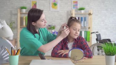 Doktor kulak burun boğaz işitme engelli genç kız işitme üzerine koymak için yardımcı olur