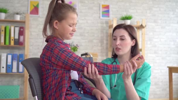 Doctor examines the hand of a teenage girl in a wheelchair after an injury close up — Stock Video