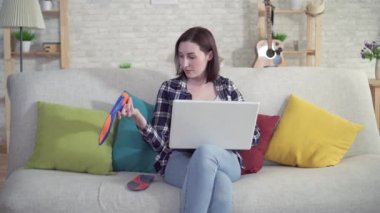 kanepede oturan genç kadın bir laptop kullanır ve elinde Ortopedik iç tabanı tutar