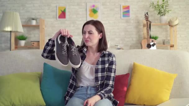 年轻女子手里拿着鞋子,闻到难闻的气味 — 图库视频影像