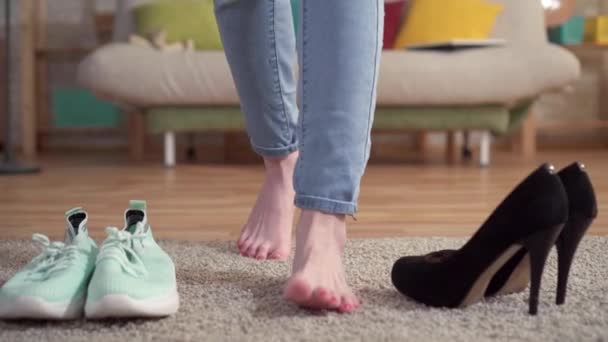 Проблема выбора женщины, что надеть между кроссовками и туфлями на каблуках — стоковое видео