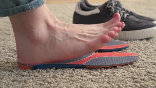 Female feet standing on the orthotics near sneakers slow mo — Stock Video