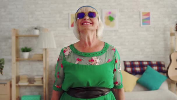 Joyeuse vieille femme pensionné rocker avec les cheveux gris dans des lunettes en regardant la caméra lente mo — Video