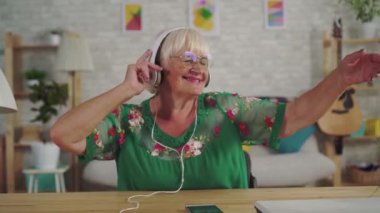 Kulaklıkta gri saçlı neşeli yaşlı kadın müzik dinlerken ve dans yakın yukarı