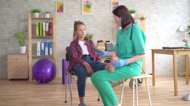 Fysiotherapeut vertelt een tiener meisje met orthopedische problemen over orthopedische inlegzolen voor flatfoot correctie — Stockvideo