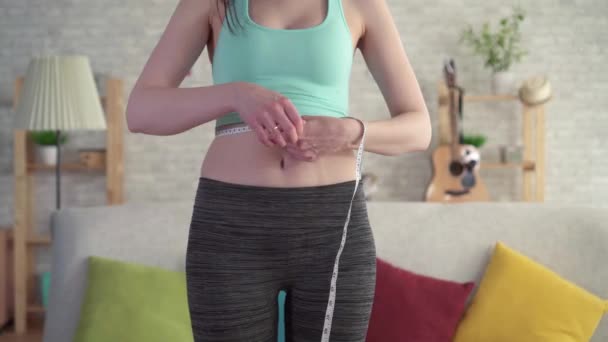 Gros plan frustré jeune femme en vêtements de sport utilise ruban à mesurer, violation de l'alimentation — Video