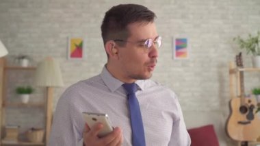 bir akıllı telefon üzerinde konuşurken oturma odasında kulağında bir işitme cihazı ile adam