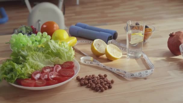 Concept of proper nutrition ,on the table are dumbbells measuring tape vegetables fruits and nuts — Stock Video