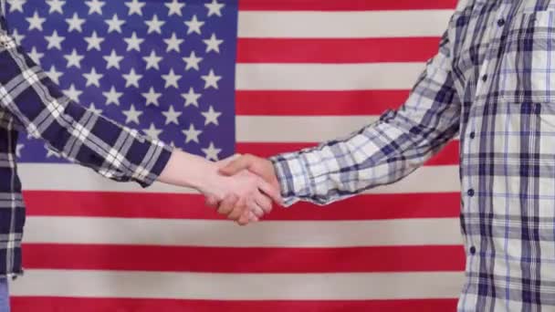 Närbild av ett handslag på bakgrunden av USA flagga — Stockvideo