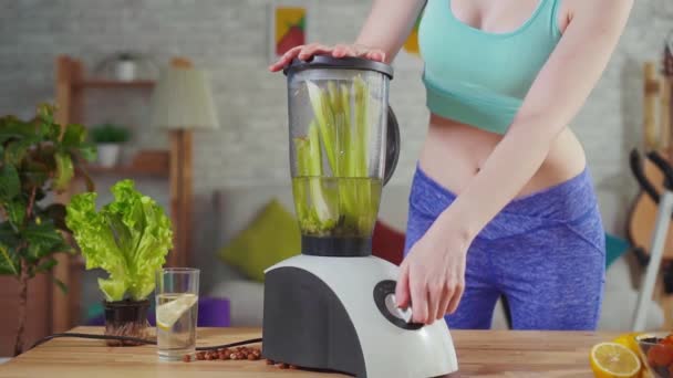 Young athletic woman throws celery in the mixer slow mo — Stock Video