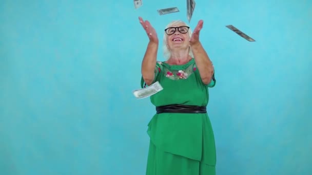 Mujer vieja atrapa billetes de papel voladores sobre fondo azul lento mo — Vídeos de Stock