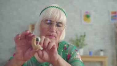 yaşlı kadın tutar ve oturan bir işitme cihazı düşünün