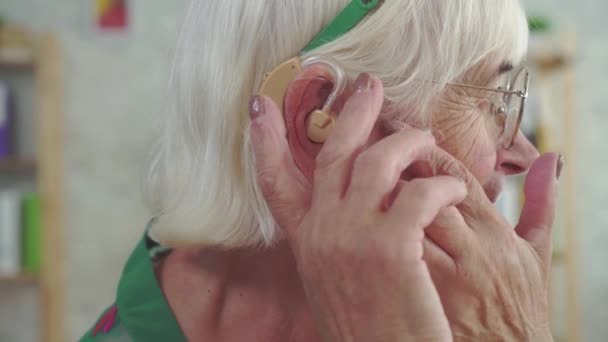 Mujer jubilada feliz usando un audífono — Vídeo de stock