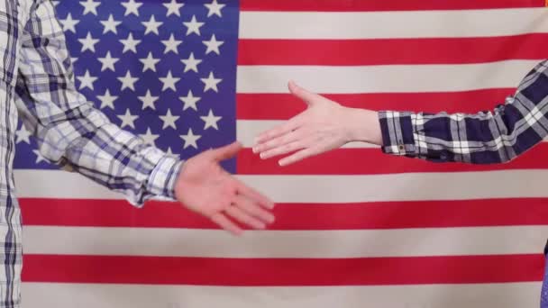 Primer plano de un apretón de manos en el fondo de la bandera de EE.UU. lento mo — Vídeo de stock