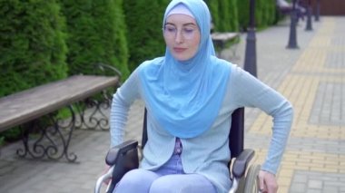 tekerlekli sandalye müslüman başörtüsü açık gülümseyen pozitif genç engelli kadın