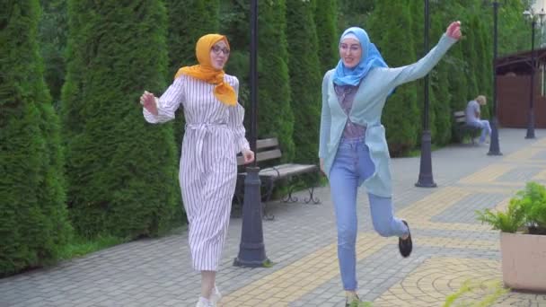 Zwei positiv lächelnde muslimische Mädchen tanzen auf der Straße — Stockvideo