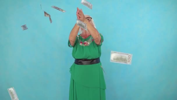 즐거운 긍정적 인 늙은 여자는 파란색 배경에 종이 지폐를 잡는다 — 비디오