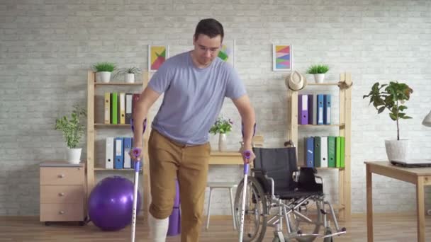 Портрет позитивного человека со сломанной ногой и костылями — стоковое видео