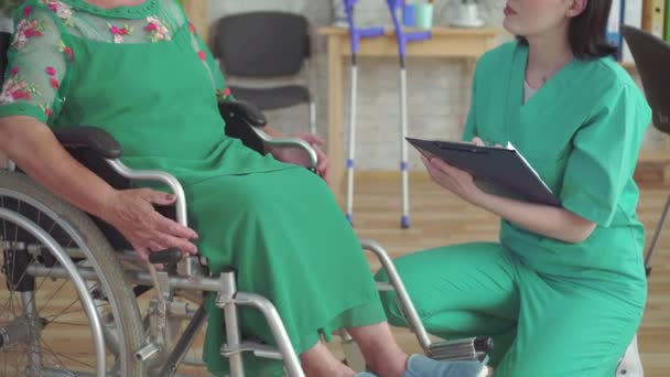 Medico controlla da vicino la salute di una donna anziana sulla sedia a rotelle — Video Stock