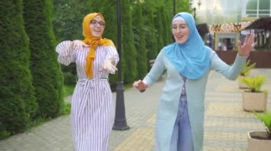 Parkta dans eden iki pozitif Müslüman genç kadın yakın çekimde