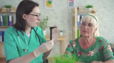 Kulak burun boğaz uzmanı yaşlı bir kadının kulağını otoskop yardımıyla inceliyor