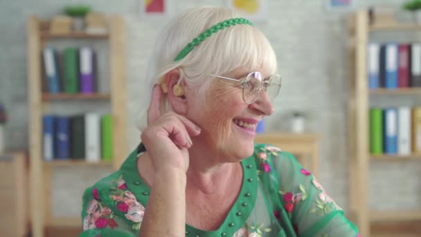 Удивлённая счастливая старуха впервые пользуется слуховым аппаратом — стоковое видео