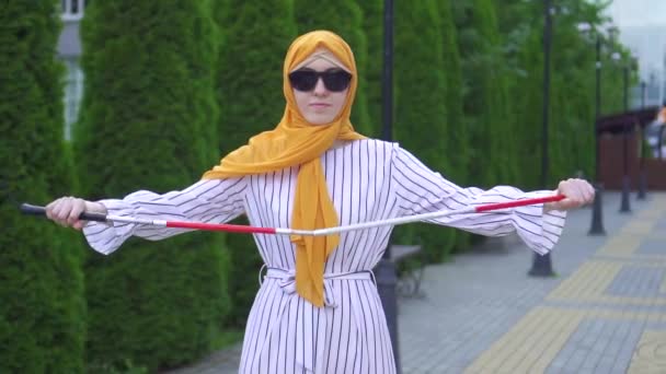 Potret seorang wanita muda buta cantik mengenakan jilbab dengan tongkat di taman — Stok Video