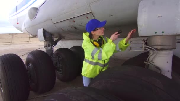 Portret vrouw specialist monteur voert technische inspectie van het vliegtuig voor vertrek — Stockvideo