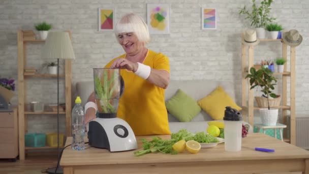 Aktive sportliche Seniorin wirft Sellerie in den Mixer und macht einen Smoothie — Stockvideo