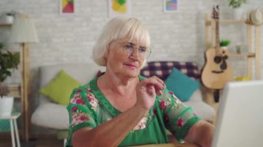 Düşünceli yaşlı kadın oturma odasında otururken bir dizüstü bilgisayar kullanır