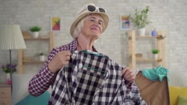 gülümseyen yaşlı kadın tatile gidiyor ve ayna önünde giysi çalışıyor yakın