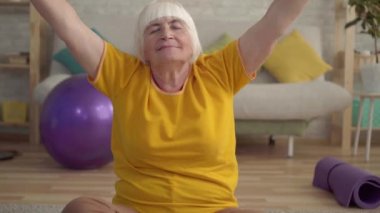 Aktif pozitif yaşlı kadın oturma odasında halı üzerinde yoga yapıyor yakın