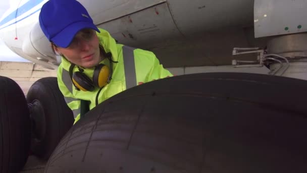 Mujer ingeniero examina los neumáticos de un avión de pasajeros en el aeropuerto antes de la salida — Vídeos de Stock