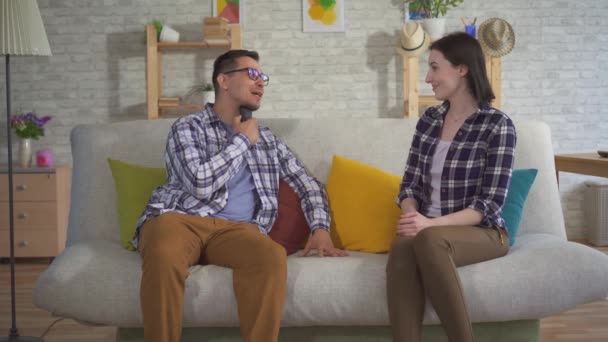 Un homme communique avec une jeune femme assise sur le canapé utilise un appareil auditif — Video