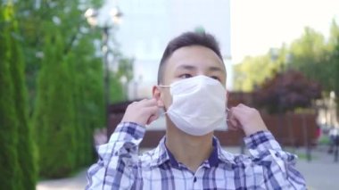 Genç Asyalı adam parkta dışında tıbbi maske çıkarır