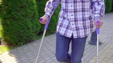 Park yavaş mo yürüyen koltuk değnekleri üzerinde kırık bacak ile genç Asyalı adam