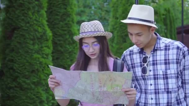 젊은 남자와 여자 아시아 여행자 와 가방 과 카드 손에 에 이 공원 — 비디오
