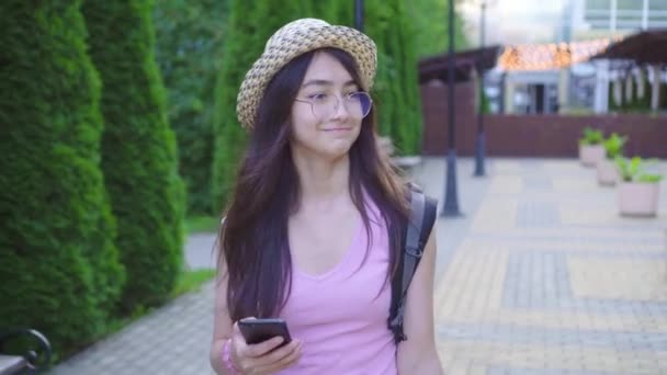 Positivo jovem mulher turista asiático aparência com uma mala e um smartphone em sua mão está no parque — Vídeo de Stock