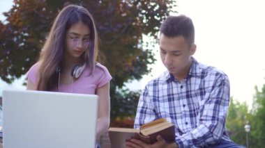 Parkta dizüstü bilgisayar ile kitap ve genç asya kadın ile genç erkek Asya öğrenci
