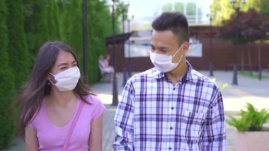 Yüzünde bir tıbbi maske iki genç Asyalı öğrenciler sokakta yürürken ve yavaş mo yakın konuşma