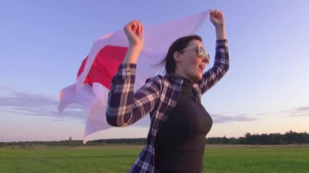 Молода позитивна жінка в сорочці проходить по полю на заході з прапором Японії повільний Mo крупним планом — стокове відео