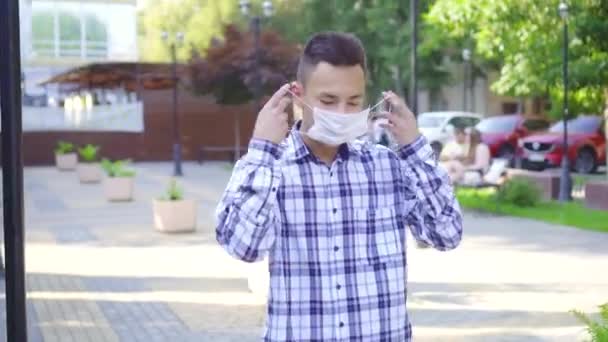 公園の路上で医療マスクを着た若いアジア人男性の肖像画 — ストック動画